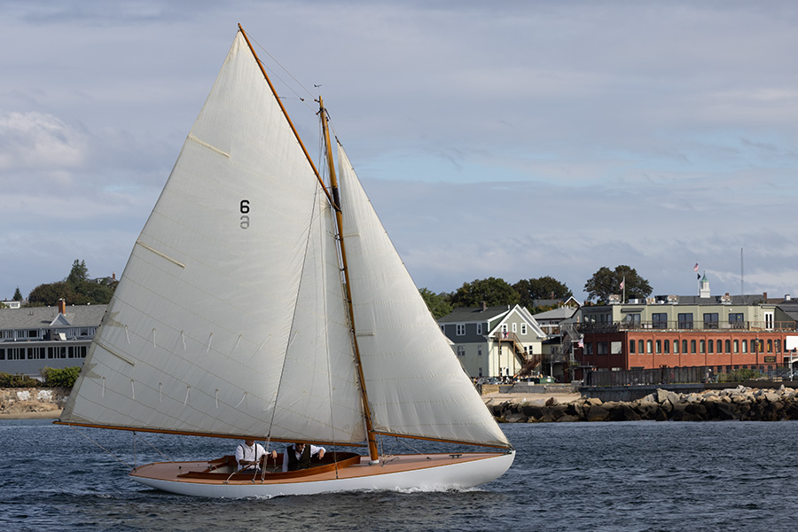 Photo of Small Beautiful Retro Sailboat Under Sail, Againts Waterfront Houses.